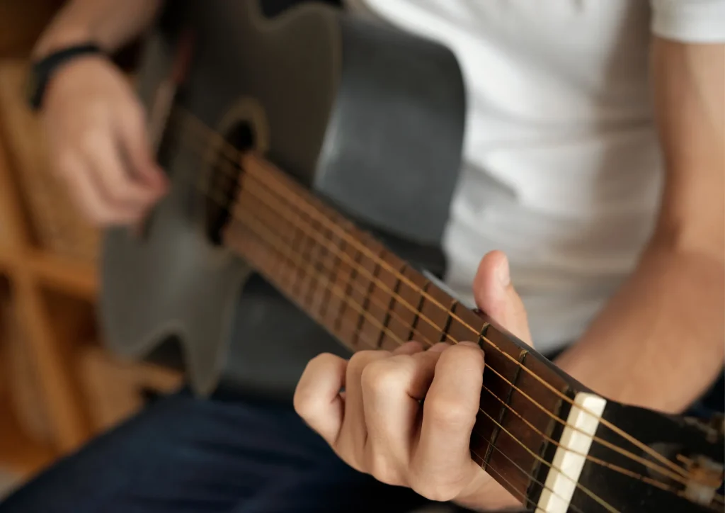 Manos tocando un acorde en una guitarra acústica