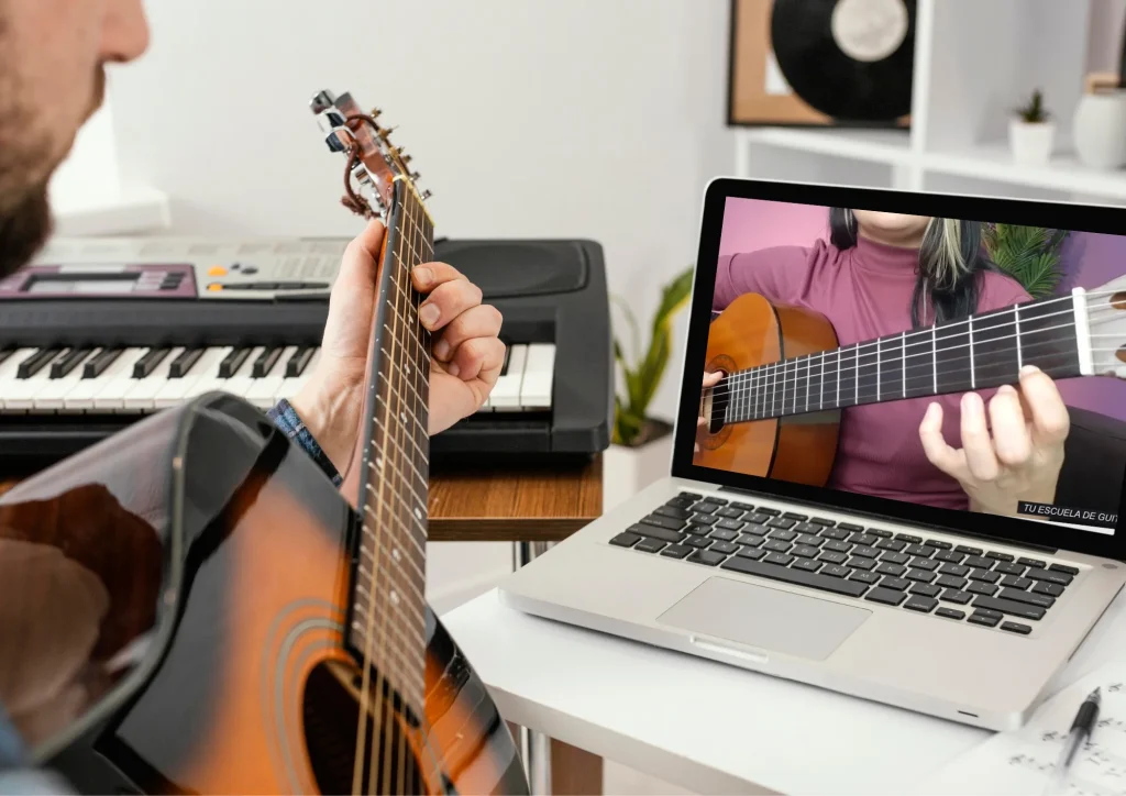 Guitarra junto a una computadora portátil con una clase en video