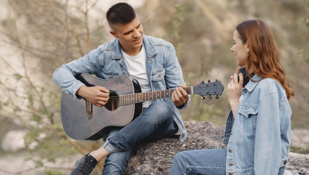 Couple standing in a sunny stonecareer. A beautiful girl is having a good time with her boyfriend. Man with a guitar.